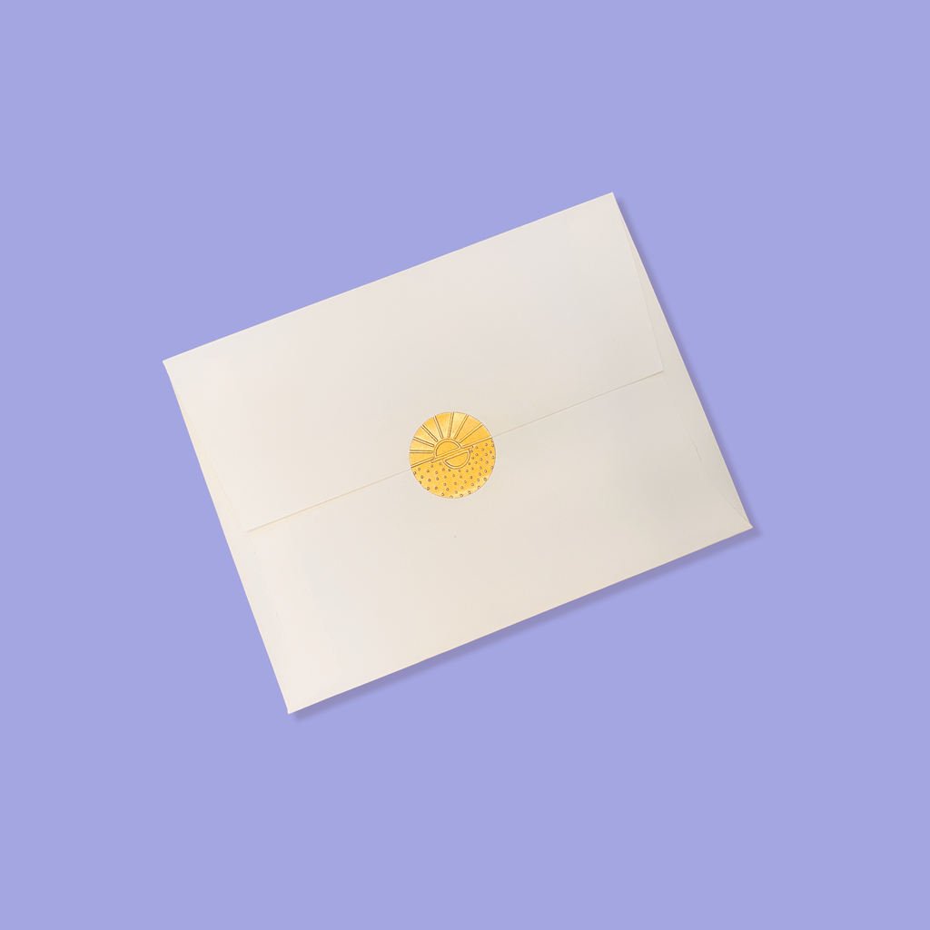 Creme colored envelope sealed with a golden vamarea sticker on a purple colored background.