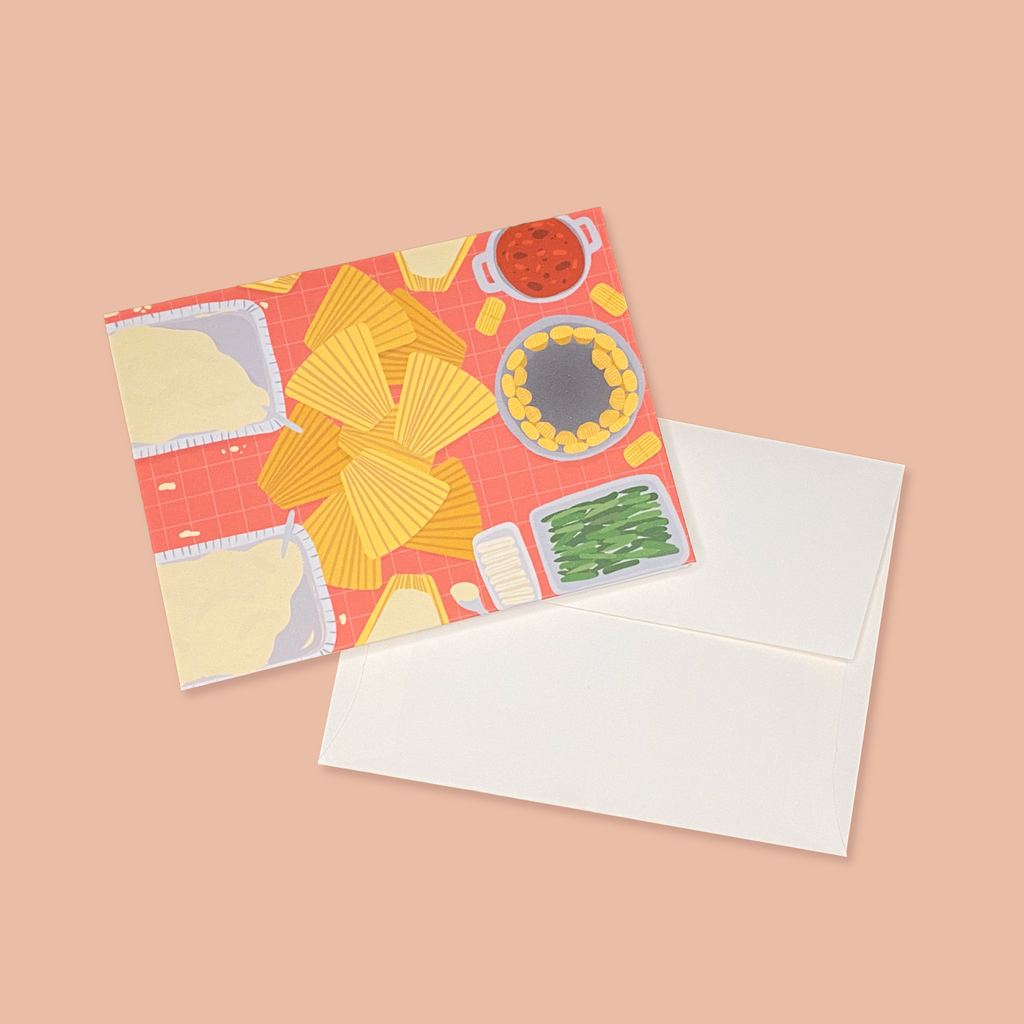 "En La Mesa Tamales" greeting card next to creme colored envelope.