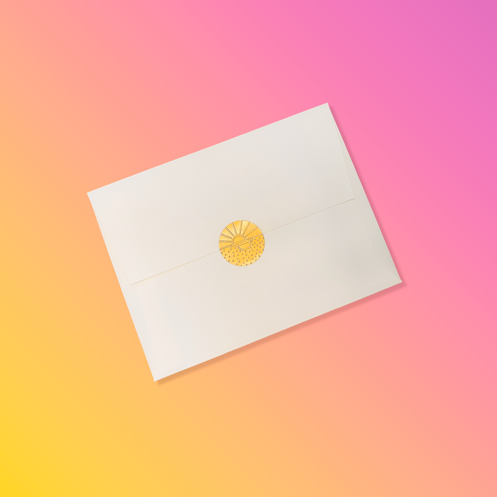 Creme colored envelope sealed with a golden vamarea sticker on a yellow to pink gradient colored background.