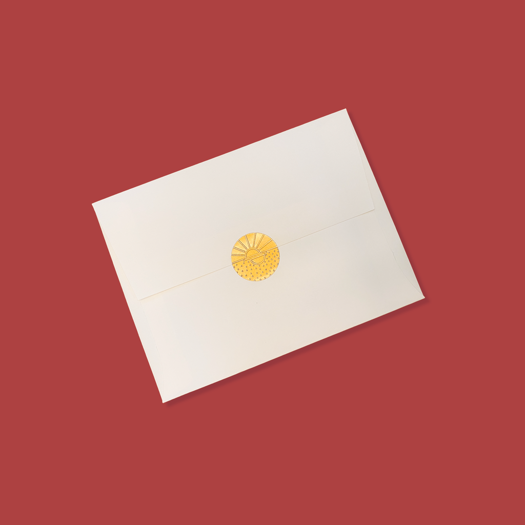 Creme colored envelope sealed with a golden vamarea sticker on a red colored background.
